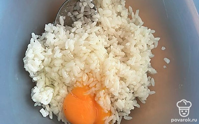 Вареный рис переложить в миску и добавить яйцо и как следует перемешать.