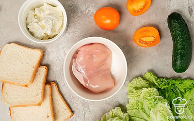 Куриное филе достаньте из морозильной камеры заранее, чтобы оно разморозилось. Огурцы и помидоры помойте и нарежьте круглыми дольками. Отложите несколько долек помидора для украшения. Листья салата промойте и обсушите. Чеснок очистите и разрежьте пополам. Подготовьте кастрюлю и сковороду.