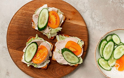 Приготовьте тосты. Отваренную куриную грудку нарежьте вдоль длинными крупными кусочками. На хлеб намажьте творожный сыр и выложите листья салата, далее положите курицу, затем овощи. Второй кусочек хлеба намажьте творожным сыром и накройте им первый.