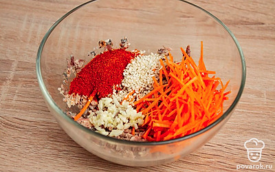 Возьмите глубокую миску. Положите в нее сайру, тертую морковь, измельченный чеснок, острый красный перец и кунжут. Хорошо перемешайте все ингредиенты.
