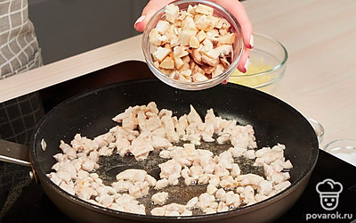 Приготовьте начинку для шампиньонов. В сковороде в масле на сильном огне обжарьте куриное филе 10 минут. Добавьте ножки грибов, жарьте еще 5-7 минут. Добавьте сметану, соль и перец. Тушите на медленном огне 5 минут. Переложите начинку из сковороды в другую емкость, слегка остудите. Добавьте половину натертого сыра и зелень. Перемешайте.