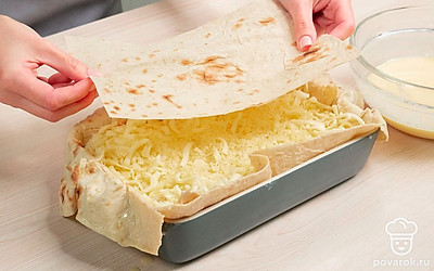 Сформируйте пирог. Распределите растопленное масло кисточкой по дну формы для запекания. Лист лаваша окуните в кефирно-яичную смесь, выложите в форму. Посыпьте частью сыра. Повторяйте слои лаваша и сыра, пока не закончатся ингредиенты. Полейте сверху оставшейся кефирно-яичной смесью. Выпекайте ачму 30 минут до румяной корочки.