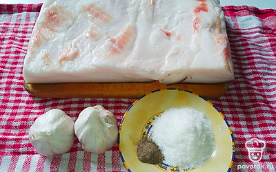 Просушите сало бумажным полотенцем и разрежьте на несколько частей. Почистите чеснок и порежьте на кружочки.