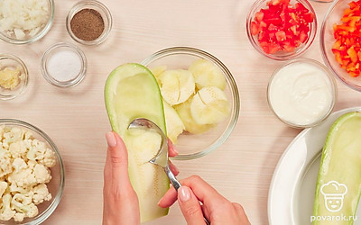 Подготовьте овощи. Кабачки разрежьте пополам, чайной ложкой аккуратно выньте из них мякоть, удалите семена и порубите мякоть ножом. Лук, перец и морковь нарежьте маленькими кубиками. Молодую цветную капусту разберите на мелкие соцветия. Помидор очистите от шкурки и нарежьте небольшими кубиками. Чеснок выдавите через пресс.