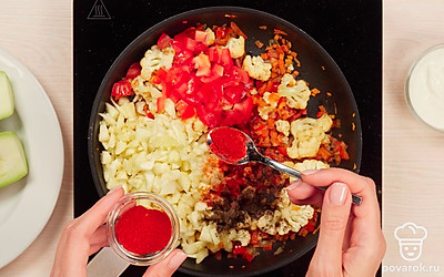 Приготовьте начинку для кабачков. В глубокой сковороде разогрейте 2 ст. л. растительного масла и добавьте морковь, лук, чеснок, болгарский перец и цветную капусту. Все перемешайте и тушите 5 минут. Затем добавьте к овощам мякоть кабачков и нарезанный помидор, а также 0,5 ч. л. соли, паприку и черный молотый перец. Перемешайте овощи и тушите еще 7-10 минут, пока не испарится вся жидкость.