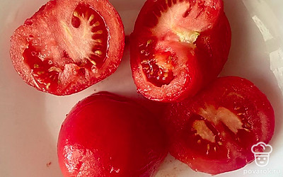 Достаем помидоры из воды и снимаем кожу. Разрезаем их на половинки.