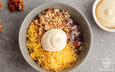 Натрите на мелкой терке желтки, измельчите грецкие орехи и нарежьте мелкими кубиками красный лук. В подходящую емкость выложите желтки, сыр, грецкие орехи и лук. Добавьте майонез и смешайте до однородности.