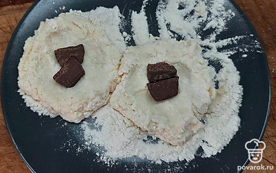 Творожную массу разделяем на равные части и в каждую выкладываем кусочки шоколада, формируем сырники. Обваливаем полученнные сырники в муке.