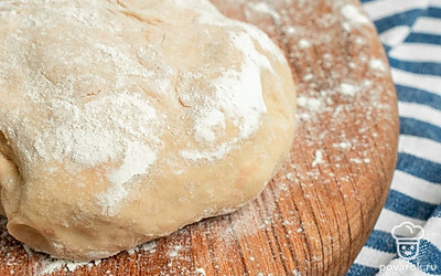 Подготовьте тесто. Всыпьте в чашу дрожжи, залейте 100 мл теплой воды. Размешайте. Дрожжи должны полностью разойтись. Влейте 250 мл воды и масло. Посолите. Добавьте постепенно муку, оставив немного для присыпки стола. Замесите тесто. Накройте полотенцем, дайте постоять 40 минут.