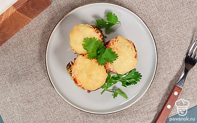 Готовые кольца кабачков, фаршированные фаршем, переложите на большое плоское блюдо и украсьте веточками молодой петрушки.