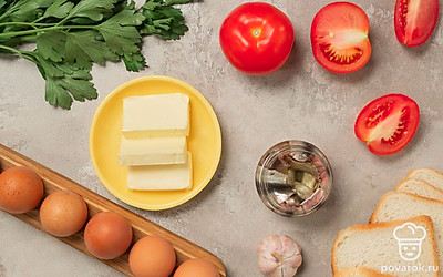 Помидоры промойте и нарежьте тонкими кружочками. Яйца промойте, просушите и сварите вкрутую, остудите, очистите и нарежьте кружочками. Кинзу промойте, просушите, листья отделите от веточек. Чеснок очистите от шелухи. Из ломтиков хлеба вырежьте кружочки диаметром с помидорные колечки. Откройте баночку с анчоусами, слейте масло.