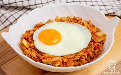 Выложите кимчи с рисом в глубокую тарелку. Сверху выложите глазунью. Подавайте готовое блюдо к столу.