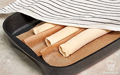 Выложите багеты на пергамент. Приподнимите пергамент и сделайте складку-барьер между багетами. По бокам положите свернутые полотенца. Сверху тоже накройте влажным полотенцем. Оставьте на 90 минут.