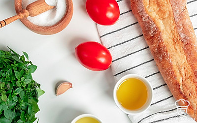 Подготовьте продукты для багета с помидором. Помидоры и базилик помойте. Багет нарежьте на ломтики. Чеснок почистите, вместе с помидорами и базиликом мелко нарежьте. Совет: Чесночное масло можно сделать самостоятельно. Для этого измельченный чеснок заливают горячим (до 180 градусов) подсолнечным нерафинированным маслом. Смесь настаивают в прохладе неделю.
