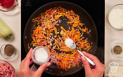 Подготовьте обжарку. В сковороду налейте растительное масло, разогрейте на среднем огне и выложите лук, чеснок и морковь. Пассеруйте овощи в течение 7-9 минут, пока морковь не станет мягкой, а лук — золотистым. Овощную обжарку посолите 0,5 ч. л. соли и перемешайте.