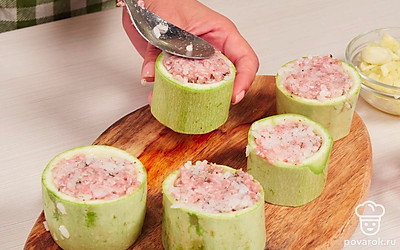 Подготовьте кабачки и помидоры. Чистые кабачки разрежьте поперек на 3-4 части шириной примерно по 5-6 см. Из каждой части выньте мякоть, оставив донышко. Сердцевину нарежьте кубиками. Очищенные помидоры нарежьте кубиками. Стаканчики из кабачков доверху наполните рисово-мясной начинкой.