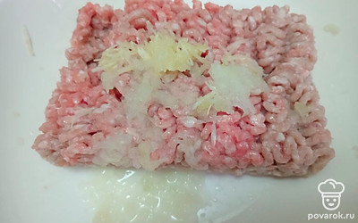 К куриному фаршу добавьте измельченный лук и чеснок.
