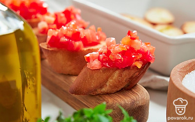 Приготовьте брускетты с помидорами и сладким перцем. Каждый ломтик багета смажьте сверху оливковым маслом. Запеките в духовке 6-8 минут. Температура должна быть 180-200 градусов. На готовый хлеб выложите замаринованные помидоры и сладкий перец.