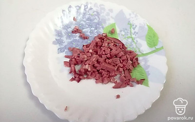 Копченую колбасу нарежьте маленькими кубиками.