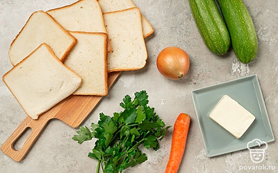 Кабачок промойте, обсушите, очистите и нарежьте мелкими кубиками. То же самое повторите с репчатым луком. Морковь сполосните, очистите от кожуры и натрите на крупной терке. Петрушку промойте, просушите и мелко порубите, а плавленые сырки нарежьте небольшими кусочками. Помидоры для подачи хорошо промойте и обсушите. Также возьмите сковороду, блендер и тостер.