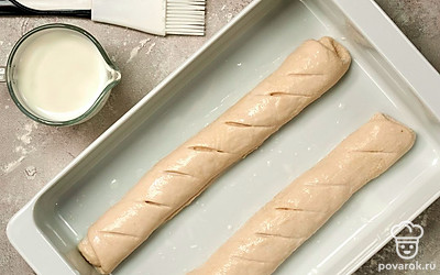 Подготовьте багеты к запеканию. Выложите багеты на присыпанный мукой противень. Накройте влажным полотенцем и оставьте еще на 40 минут. Сделайте на багетах несколько надрезов наискосок.