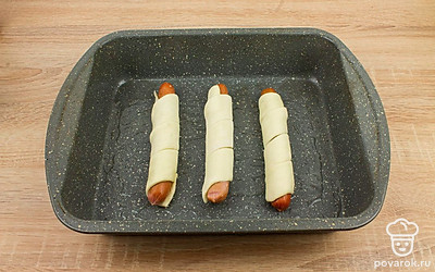 Смажьте противень растительным маслом. Выложите на него хот-доги и смажьте их взбитым яйцом.