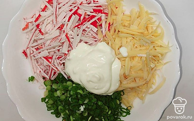 Натрите крабовые палочки и сыр на крупной терке. Зелень нашинкуйте. Соберите все в глубокой тарелке и добавьте сметаны. Хорошо вымешайте.