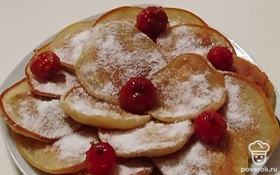Готовые оладьи присыпьте сахарной пудрой, украсьте и подавайте к столу.