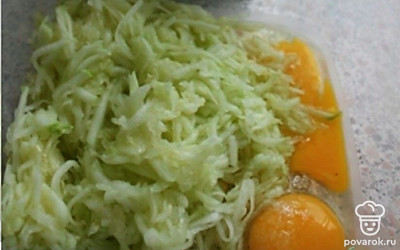 Кабачок почистите и натрите на крупной тёрке. Вбейте в чашу с тёртым кабачком два яйца. Посолите.