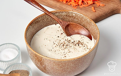 Приготовьте тесто для оладий. Возьмите глубокую емкость и соедините в ней лук, воду, соль. Тщательно перемешайте. Всыпьте муку, добавьте специи по вкусу. Перемешайте.