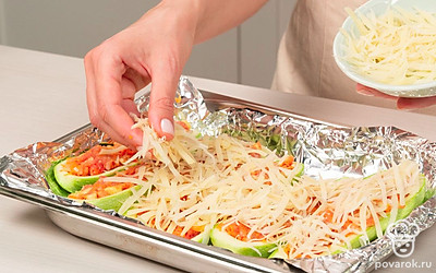 Подготовьте к запеканию. Застелите противень фольгой, выложите кабачковые лодочки и каждую заполните начинкой. Сверху посыпьте сыром.