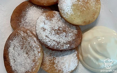 Подавайте порционно. Оладьи посыпьте сахарной пудрой, рядом положите сметану. Приятного аппетита! 