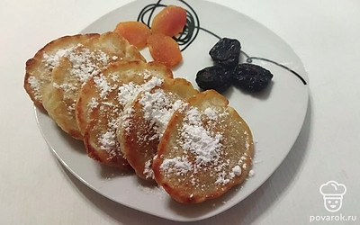 Оладьи выложите на тарелку, посыпьте сахарной пудрой и украсьте сухофруктами. Подайте теплыми к столу.