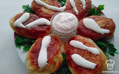 Готовые оладьи выложите на большую тарелку по кругу. Украсьте веточками петрушки в промежутках, а в центр посуды установите соусник со сметаной. Подавайте теплыми к столу.