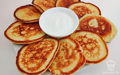 Готовые оладьи украсьте сметаной.