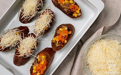 Выложите начинку в багет и запеките его. В середину каждого кусочка равномерно выложите начинку и посыпьте тертым сыром. Подготовленные кусочки багета выложите на противень и поставьте в духовку на 10 минут.