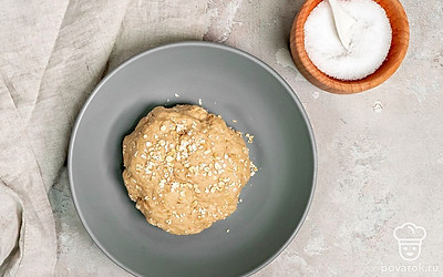 Сделайте тесто. В миску с пшеничной и овсяной мукой добавьте соль и дрожжи. Перемешайте и влейте теплую воду. Еще раз тщательно все перемешайте, чтобы получилась немного липкая однородная масса. Миску накройте пищевой пленкой и уберите на 12 часов в теплое место. За это время тесто должно подняться и на его поверхности появятся пузырьки.