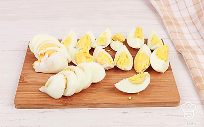 Очистите отварные яйца от скорлупы и нарежьте их четвертинками