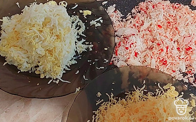 На мелкой терке натрите вареные яйца, сыр и крабовые палочки.
