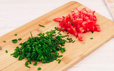 На разделочной доске мелко нарежьте помидор и пучок зеленого лука.