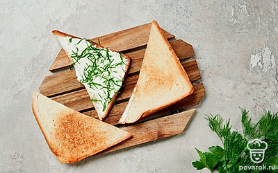 Подготовьте начинку. Чеснок разрежьте пополам и смажьте им обжаренные ломтики хлеба. Намажьте половину треугольных кусочков сыром, порежьте зелень и посыпьте ею бутерброды. Сверху прикройте пустыми хлебными половинками.