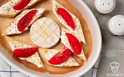 Запеките багет с сыром. На середину пергамента выложите сыр, вокруг него разложите кусочки багета. На них выложите дольки помидоров, посыпьте их солью и прованскими травами. Запеките сыр с багетом в духовке при температуре 200 градусов в течение 10 минут.