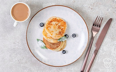 Выложите ароматные оладьи на небольшую тарелку, посыпьте сахарной пудрой, украсьте ягодами и подайте к столу вместе с чаем, кофе или какао.