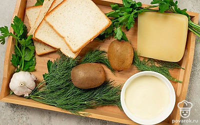Подготовьте необходимые продукты, удобно расположите их на рабочем столе. Почистите чеснок и киви. Чеснок пропустите через пресс, киви нарежьте кружочками. Зелень вымойте, обсушите, измельчите. Кусочки хлеба разрежьте по диагонали.