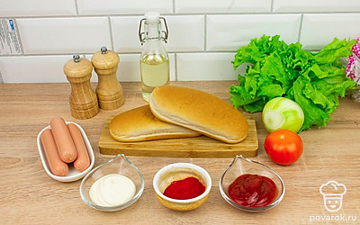 Очистите репчатый лук, снимите упаковку с сосисок. Помойте помидор и листья салата.