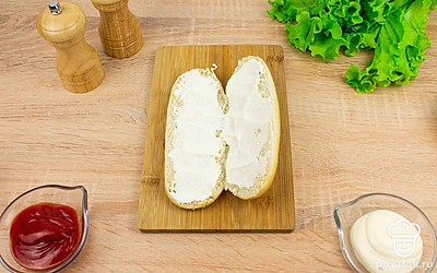 Разрежьте булочки для хот-догов вдоль по горизонтали, не дорезая до конца. Смажьте каждую половинку булочки майонезом.