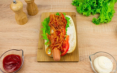 Затем выложите ломтики помидора и жареный лук. Таким же образом сделайте второй хот-дог.