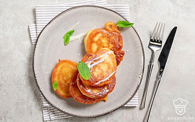 Аккуратно переложите оладьи горкой на основную тарелку. Подавайте ароматную выпечку горячей: со сметаной, вареньем или сгущенным молоком. 