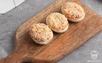 Смешайте начинку в отдельной посуде: соленые огурцы, яичный желток, икру, сыр, майонез, соль и перец. Оставьте немного красной икры для украшения закуски. Мешайте до тех пор пока она не станет плотной густой массой. Затем распределите ее по яичному белку.