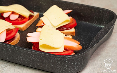 Приготовьте тост. Положите ломтики хлеба на противень, нанесите на каждый кусочек немного кетчупа. Сверху выложите помидоры, на них — сосиски, накройте ломтиком сыра. Отправьте в духовку на 5-7 минут.